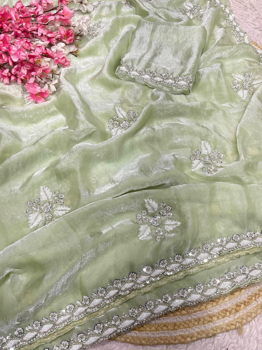 Light green fabric with silver embroidery and pink flowers in the corner