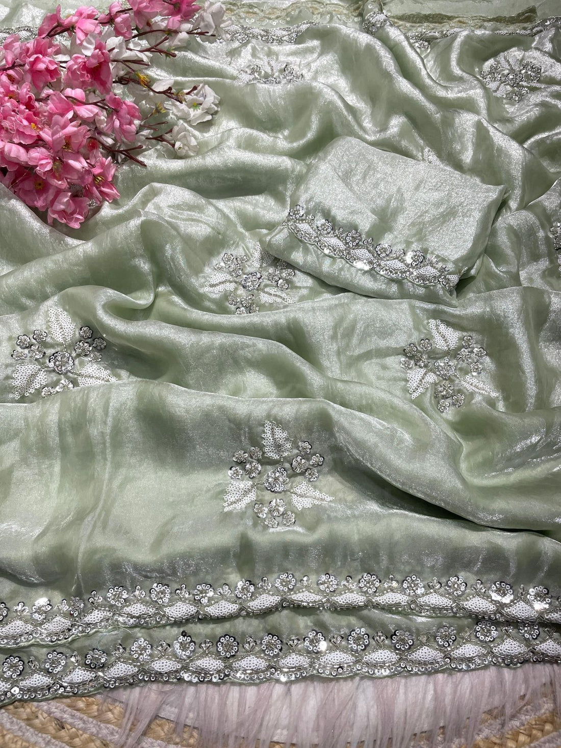 Light green fabric with silver embroidery and pink flowers in the corner