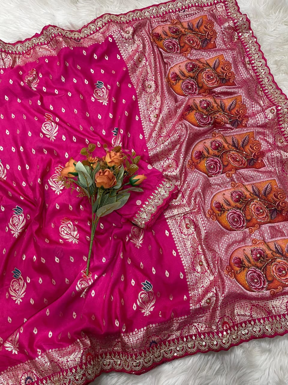 Embroidered pink fabric with floral design on a white surface with decorative elements.